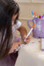 A young girl colors her Henry the Goose digital watch using markers, bringing the design to life with vibrant colors.